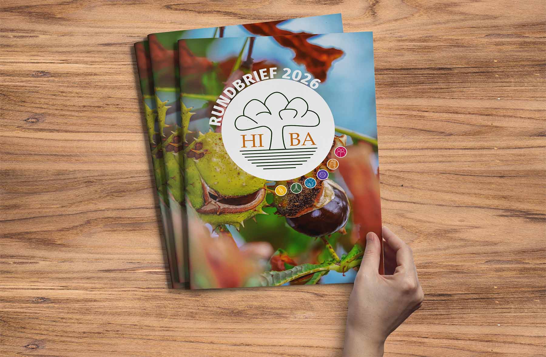 Foto des HIBA-Rundbriefes 2026 auf einem Holztisch mit einer Hand, die ihn öffnet.